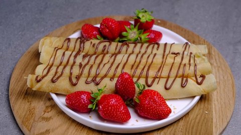 Rotating crepe rolls with chocolate, strawberries and blackberries