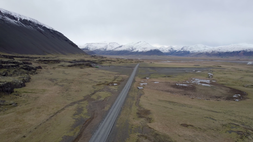 Following a highway across brown autumn ground towards glorious snow capped mountains