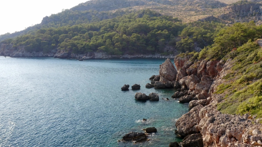 Flight along rocky seashore reveal secluded Turkish azure blue water bay