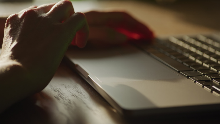 Woman hand entering the shot and swiping sideways on the laptop touchpad in sunset light