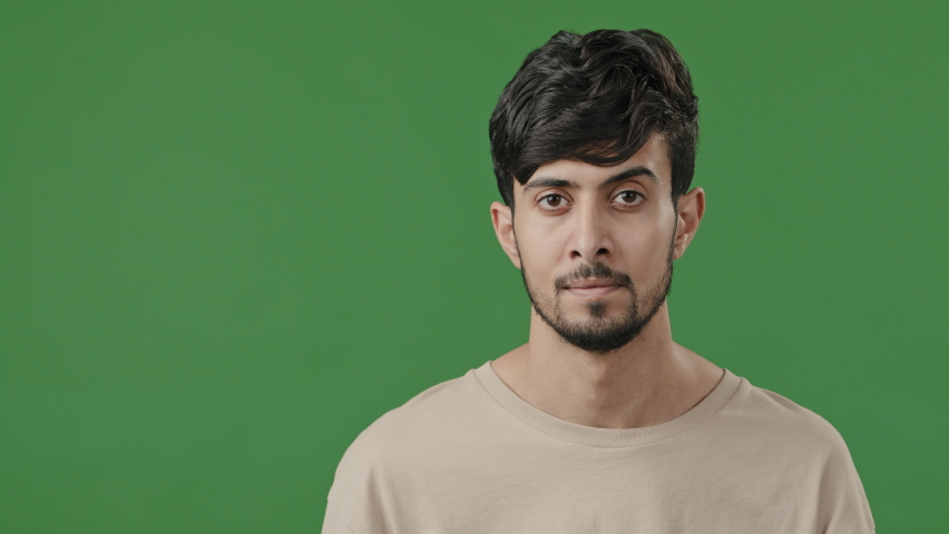 Indian young handsome man stands on green background holds copy space on hand points at empty place arabic smiling brunet guy recommend using mockup blank area for advertisement offer imaginary object Royalty-Free Stock Footage #1091540673