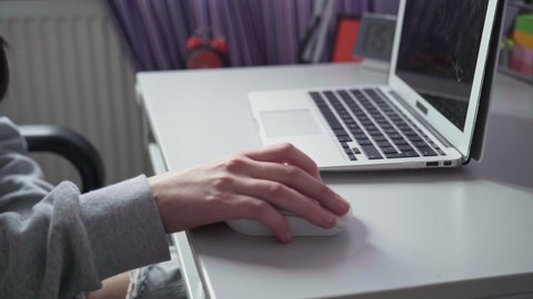 A woman's hand operates a computer mouse while surfing the Internet.