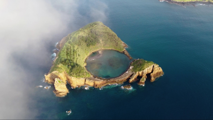 Aerial panoramic view Azores, Portugal. The crater of an old underwater volcano near San Miguel, Vila Franca do Campo. Drone flies through the clouds high quality 4k footage. Royalty-Free Stock Footage #1091542237