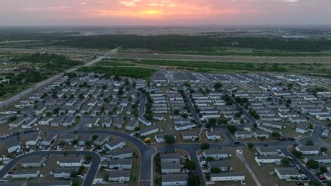 Colorful sunset over rural mobile home community in Western USA. Low income housing in America. Aerial truck shot.