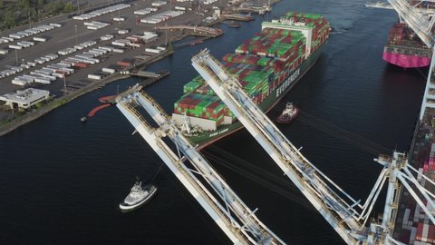 Tugboats And Cargo Ship Fully Loaded With Intermodal Containers For Shipping On Blair Waterway. Husky Terminal In Port Of Tacoma, Washington. aerial orbiting (ascending shot)