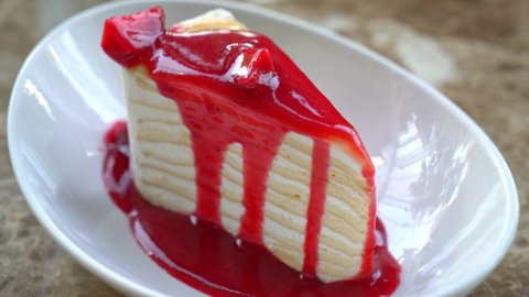 vanilla crepe cake with raspberry and strawberry sauce on plate