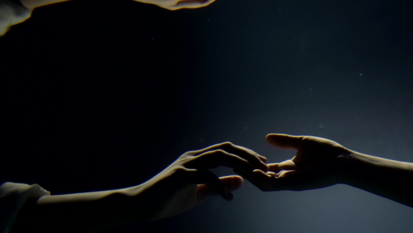 mysterious underwater shot, hands of two people are holding to each other in dark water of sea Royalty-Free Stock Footage #1091547907