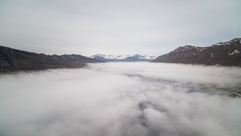 Establishing Aerial View Shot of Fjords surrounded by mountains covered in fog, Iceland