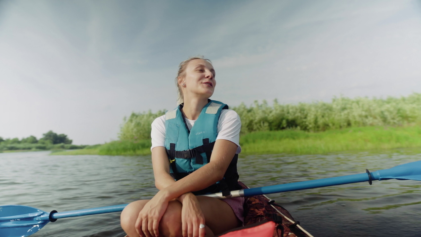 A young woman is paddling a kayak on the river against a beautiful landscape. Travel. Tourism. | Shutterstock HD Video #1091550437