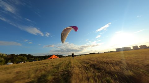 Paraglider lands on the green field, paraglider folds 