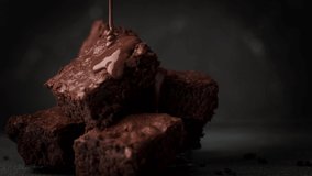 Pouring melted chocolate on cake biscuits in a slow motion. Brownies with chocolate icing on black background - Powered by Shutterstock - Get 15% off with code: PIKWIZARD15
