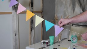 Creative studio, handmade holiday decorations. A person glues paper triangles on a thread for a birthday - Powered by Shutterstock - Get 15% off with code: PIKWIZARD15