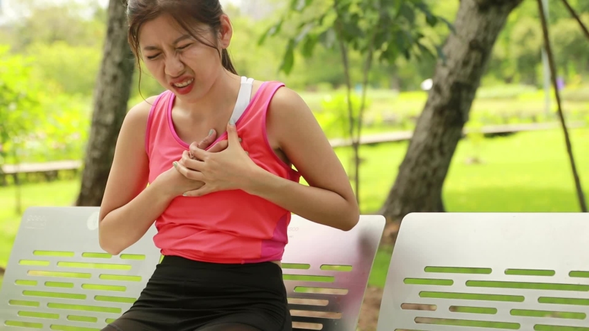 Asian young woman jogging in the garden, losing sweat and running too much, has a sudden onset of heart disease, walks to rest in a chair exhausted.
 | Shutterstock HD Video #1091557923