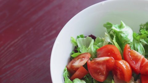 Close up of healthy lunch with radishes, tomatoes, lettuce, aromatic herbs and olives. Cooking healthy food in the kitchen. Fresh vegetable salad. Vegetarian diet. Woman cuts and mixes salad.