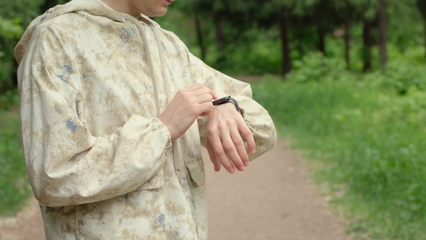 Smart watch on a man's hand. Man touching a smart band screen, checking heart rate and pulse before training. Summer outdoor activities | Shutterstock HD Video #1091564413