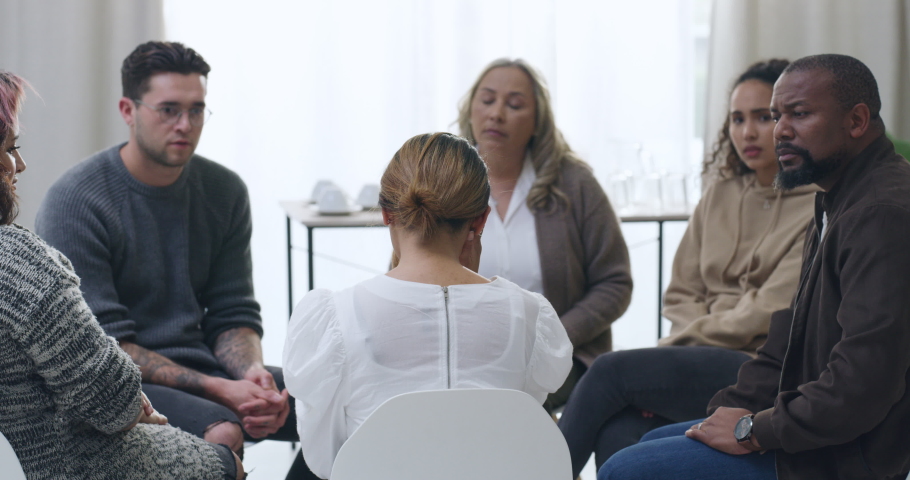 Woman crying and being comforted during group therapy. Upset and anxious patient sharing trauma story with diverse people and victims. Stressed, seeking help and support for mental health and wellness