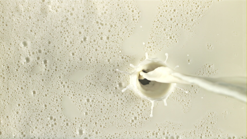 A stream of milk flows with splashes and air bubbles. On a white background. Filmed on a high-speed camera at 1000 fps.