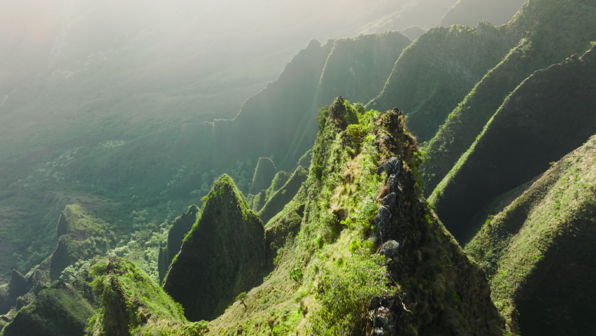 Breathtaking Hawaii nature on Kauai garden island. Magical green mountain ridge. Epic green high sharp peaks with text space background. Golden sun rays shining on steep green cliffs sunny landscape