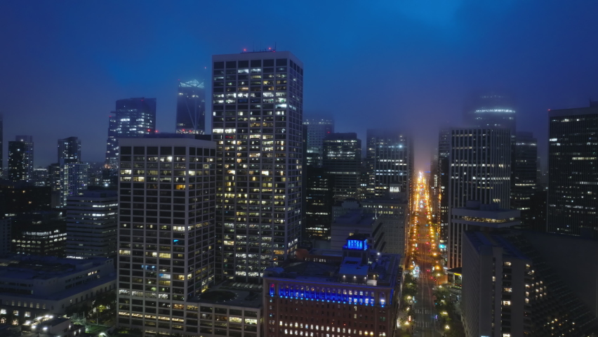 San Francisco downtown at night time illumination. Beautiful aerial financial district in San Francisco city. Drone flying over a city night lights with high skyscrapers buildings covered with clouds