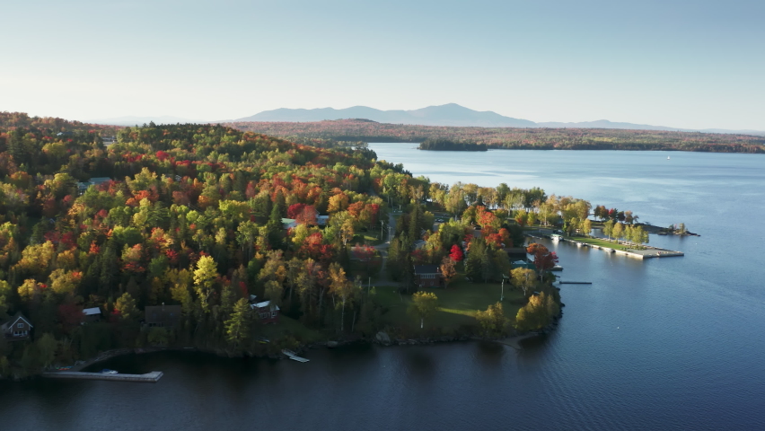 Beautiful still water surface at autumn forest with foliage trees. Aerial view blue lake at colorful forest. Cinematic Moosehead Lake coast with fall forest, Maine landscape with fresh blue lake water
