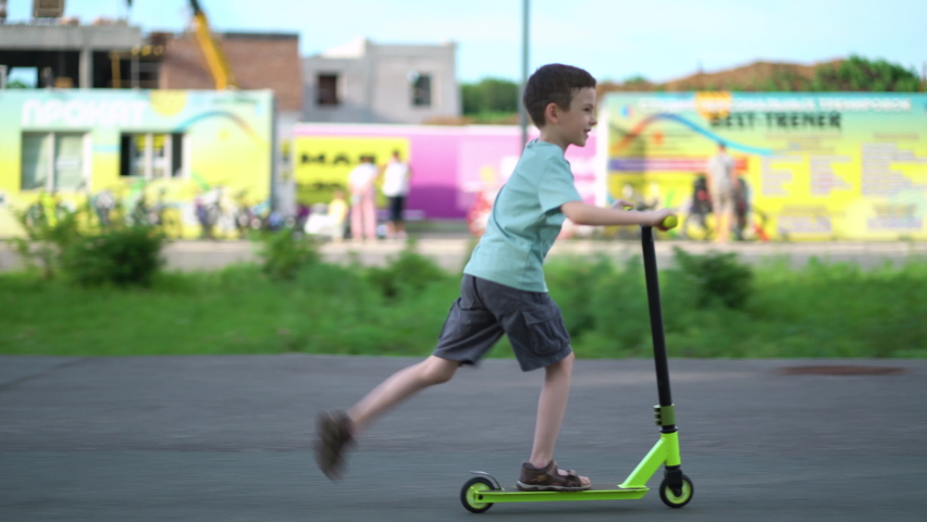 Boy riding a children's scooter on city street on weekend. Royalty-Free Stock Footage #1091568977