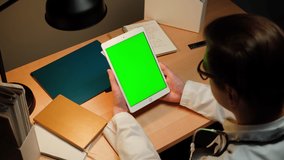 Doctor using gadget tablet with green chroma key screen. Man therapist working, watching video. Healthcare and medicine concept. 