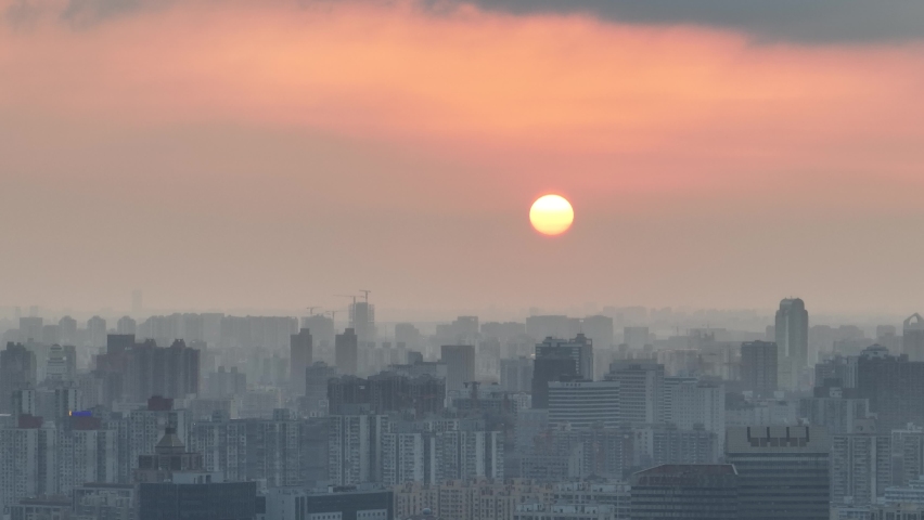 Drone aerial view of City in the dusk and the orange sunset glow. Flying over the city with rows of buildings, beautiful sunset Shanghai China. Business, travel and life style concept b-roll footage.
