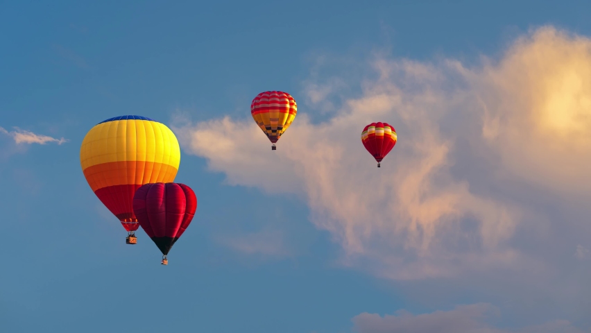 Hot Air Balloons Flying. Multicolored hot air balloons with basket floating against the blue sky over high mountain. aerial view. Royalty-Free Stock Footage #1091571235