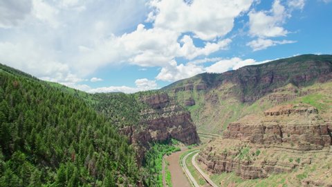 Flying Over Rocky Canyon Cliffside Covered In Trees Revealing Epic Beautiful Wide Open Gorge With Healthy Green Alpine Trees During Warm Hot Summer Day In Glenwood Canyon Colorado USA. Drone Shot.