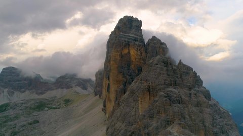 Aerial view across clouds over majestic Tre Cime mountain peak rock formation scenery in South Tyrol Dolomites