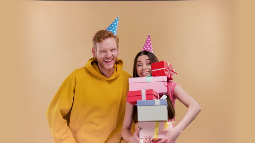Funny woman holding a huge amount of gifts that a man gave her isolated over beige background | Shutterstock HD Video #1091581995