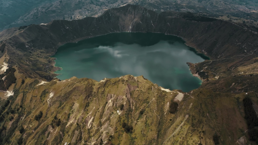 Cinematic aerial view over volcano landscape and crater lake during cloudy day in Ecuador