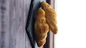 Vertical video, Zoom in shot, Two delicious croissants stacked on black marble slab