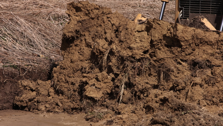 Construction machinery equipment, earth building bulldozer, earthmoving machine technology, industrial erection concept. Bulldozer working on mud at a construction site. Close up
