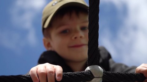 The boy climbs the large grid of the playground