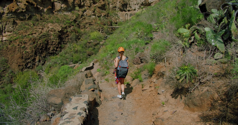 Tourist hiker caucasian girl walks enjoying rocky hiking path. Slow motion. Barranco del Infierno, near to Adeje town. Tenerife.