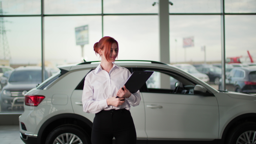 portrait of auto sales female manager holding keys in front of a new car, smiling and looking at camera Royalty-Free Stock Footage #1091591499
