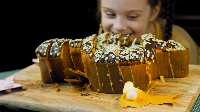 The girl is happy and flirting when she sees the chocolate cake. On the background are purges of Easter made of paper. Macro and slider shooting | Shutterstock HD Video #1091596259