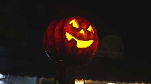 Halloween Pumpkin Lantern in an Amusement Park Glowing at Night. Halloween Decoration. Mystery Night Atmosphere. Handheld Shot