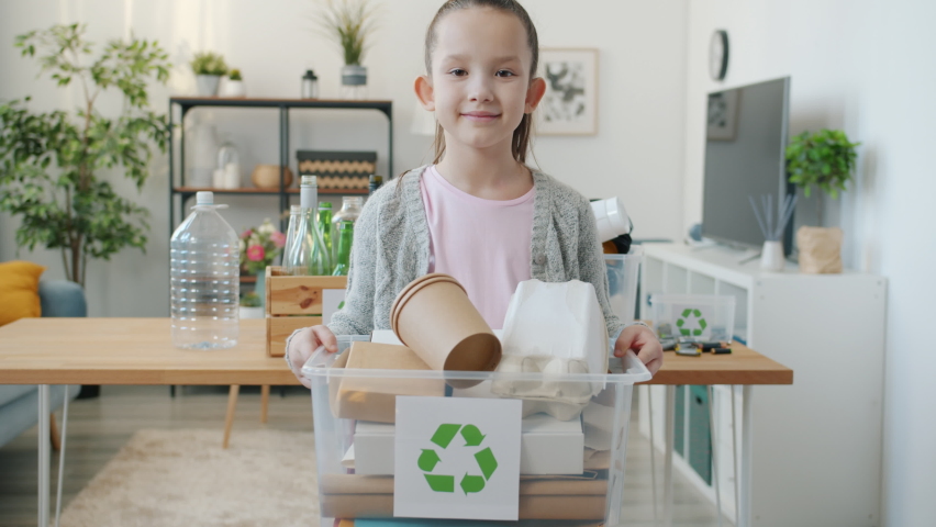 Slow motion portrait of little girl holding container with waste for recycling standing in apartment alone caring for ecology. Childhood and environment concept. Royalty-Free Stock Footage #1091600193