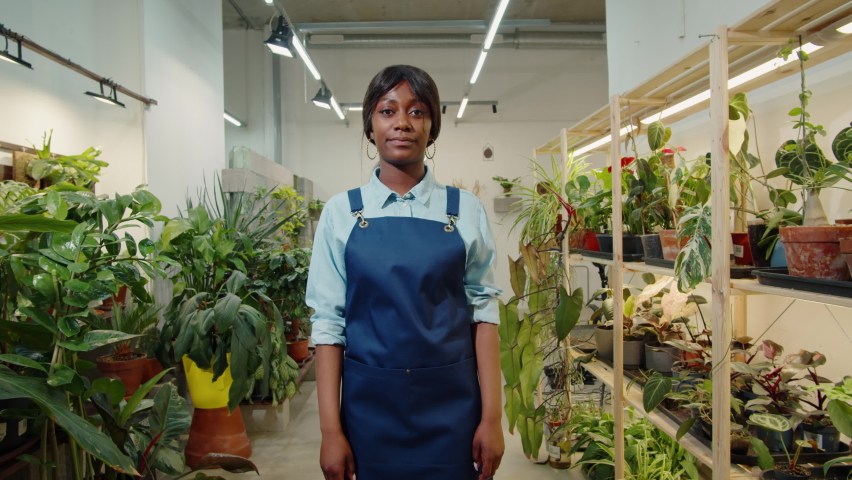 Florist African American woman portrait, flower shop. Greenhouse worker smiling, happy botanist close-up, small business owner. Gardener working in plant store.  Royalty-Free Stock Footage #1091601465