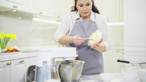 A women cook adds a butter to prepare dough or cream in a mixer bowl. cooking courses. bread and dessert recipes. family business. online lessons for cooks.
