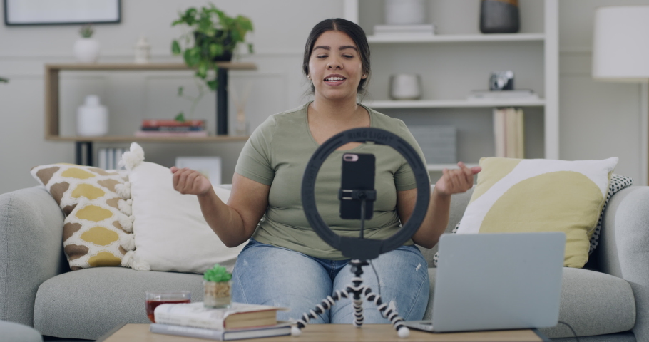 Young plus size female vlogger making video content for social media using her phone and ring light in the living room at home Curvy influencer educate and motivate her followers on body positivity | Shutterstock HD Video #1091604693
