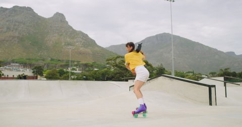 Carefree passionate skater spinning and listening to music on boombox while rollerskating in skate park and rink. One cool young fun woman enjoying free time and dancing while wearing rollerskates