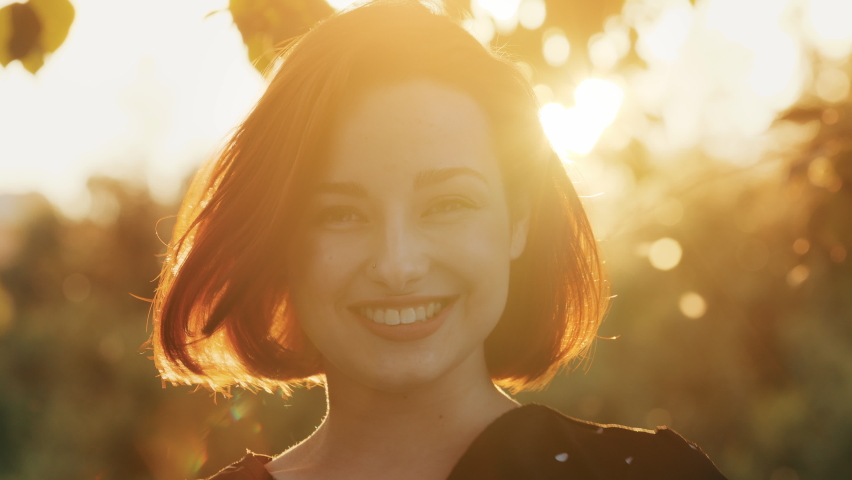 Outdoors female portrait of redhead attractive beautiful girl stylish woman with short hair happy caucasian pretty young girlfriend model smiling soft posing outdoors moves in shining sunlight sunset | Shutterstock HD Video #1091609283
