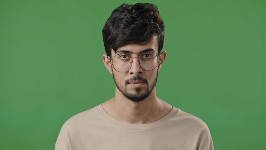 Clever arab man teacher in eyeglasses think hold hand on chin deep in thought indian guy student professor stand on green background fix spectacles generate idea dreaming smart face close-up portrait | Shutterstock HD Video #1091609311