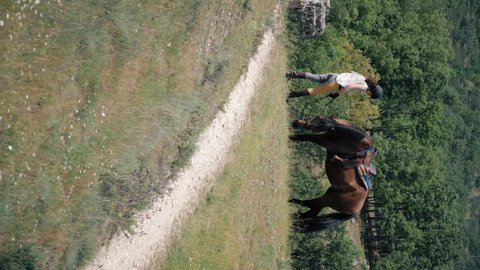 Vertical shot of Female horse rider with yellow breeches and her brown andalusian horse grazing on a spring day in the mountains.