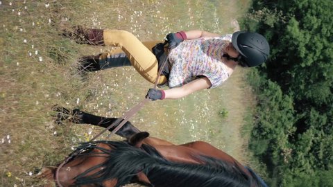 Vertical shot of Female horse rider with yellow breeches, chocolate labrador retriever and brown andalusian horse grazing on a spring day in the mountains.