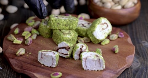 put fresh Turkish delight with crushed pistachios and chocolate on a board, fresh Turkish delight with green pistachios is put on a wooden surface
