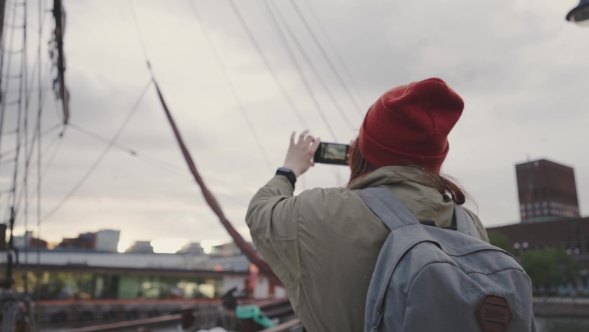 A young woman walks along the embankment. ship dock in oslo norway.